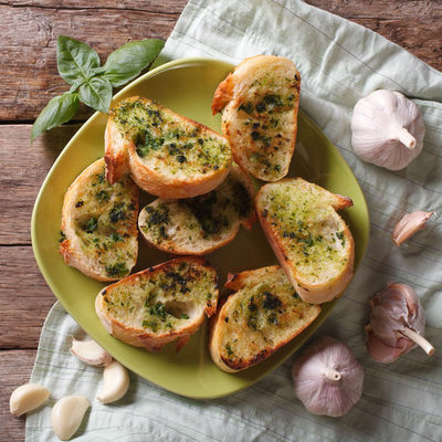 Garlic bread is a flavored bread of Italian origin that includes thickly sliced bread, oil or butter, and garlic. The bread used for this dish is generally a baguette as it provides a crispy and crunchy texture.