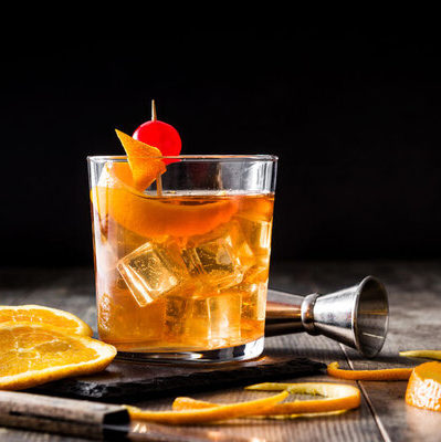 The old fashioned is a cocktail that contains whiskey, soda water, bitters, ice, and orange garnish.