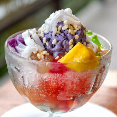 Halo-Halo is a Filipino dessert made with crushed ice, condensed milk, ube (purple yam), sweetened beans, coconut, sago, gulaman, pinipig (flattened rice), taro, flan, and fruit slices.