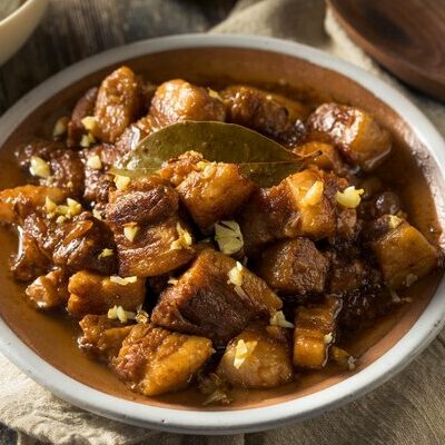 Adobo is a Filipino dish made with a base of meat and simmered in a concoction of vinegar, soy sauce, and a variety of spices and herbs.