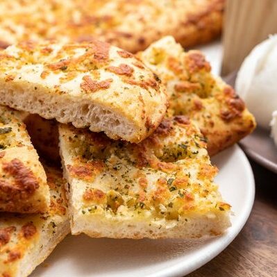 Focaccia is a type of bread of Italian origin. It is a leavened flatbread made with white flour and baked in an oven. It is often topped with salt, olive oil, rosemary, olives, cheese, tomatoes, or even onions.