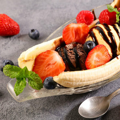Banana split is a type of dessert that falls under the category of sundaes. It consists of three ice cream scoops of vanilla, chocolate, and strawberry, as well as chocolate sauce, strawberry sauce, and pineapple sauce.